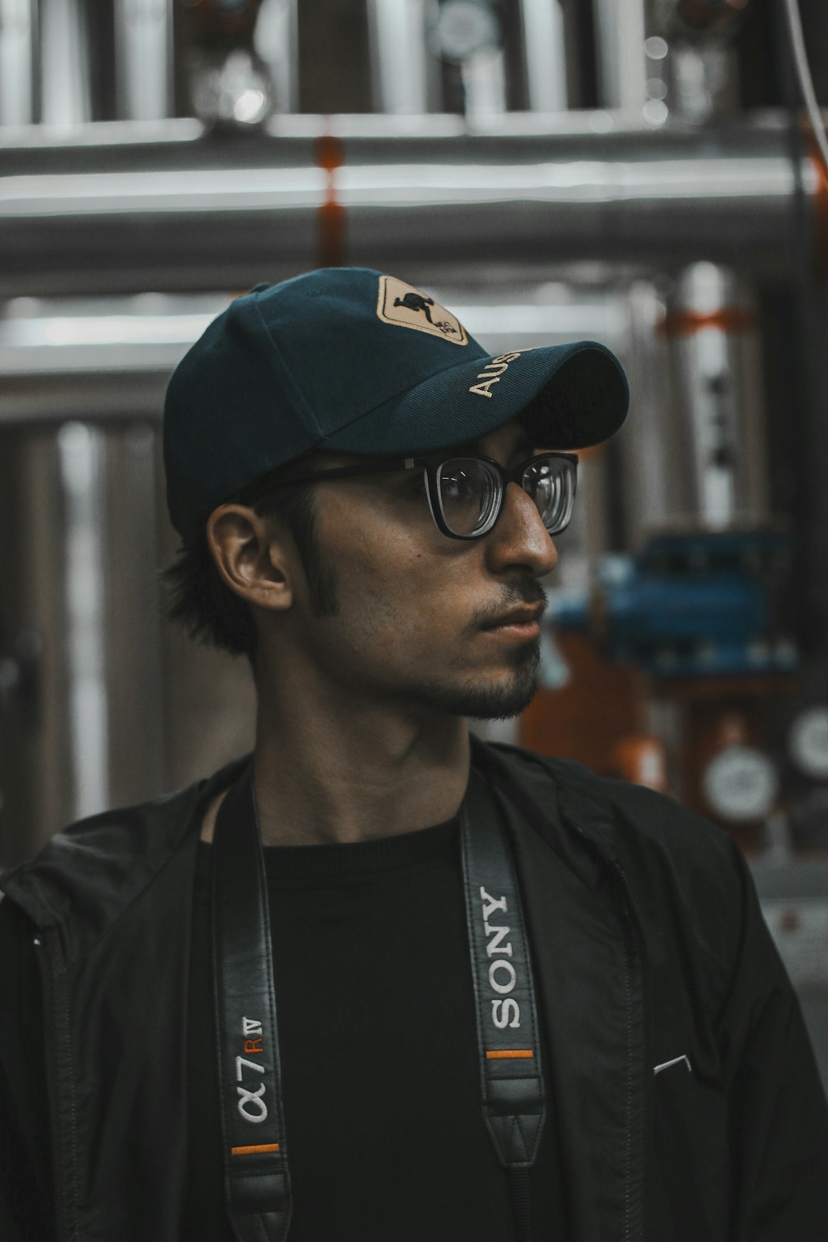 a man wearing a hat and glasses in a factory