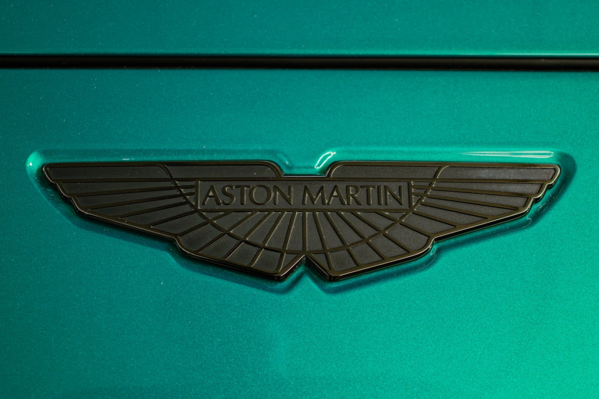 An aston martin logo on teal paint.