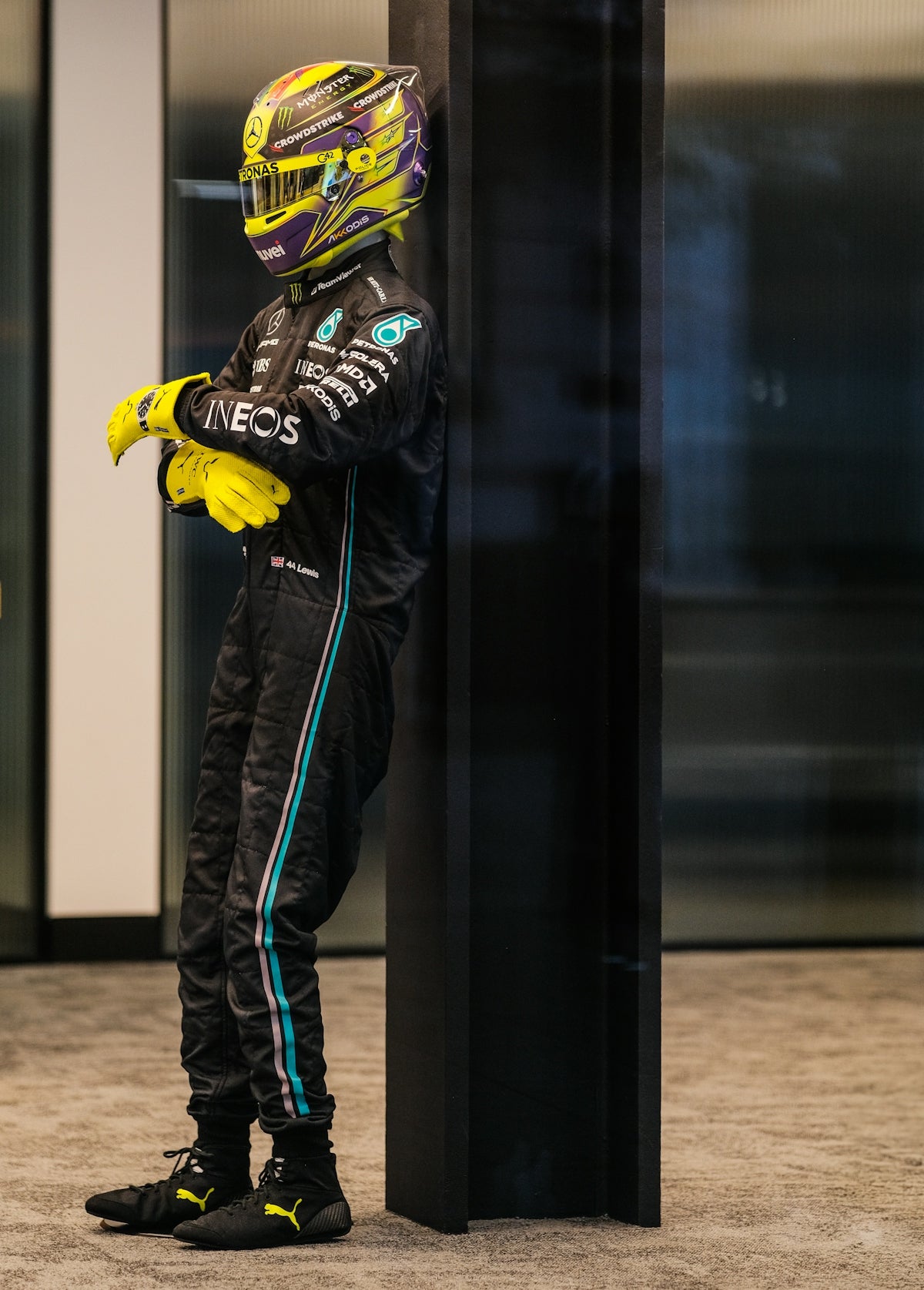 Formula 1 driver in racing suit leaning against wall