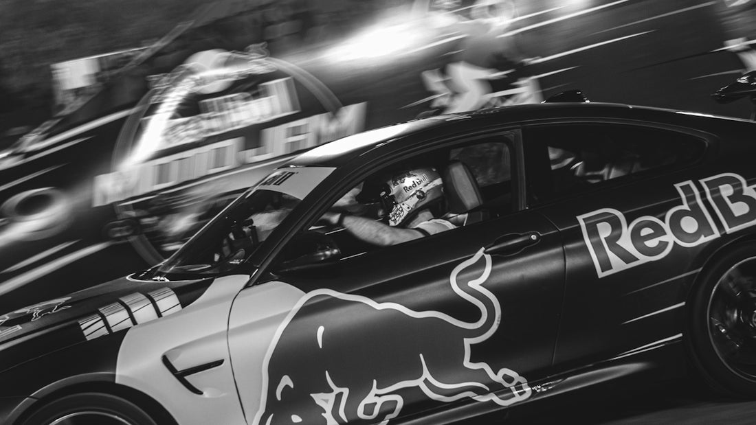 Two race cars with red bull logos speeding at night