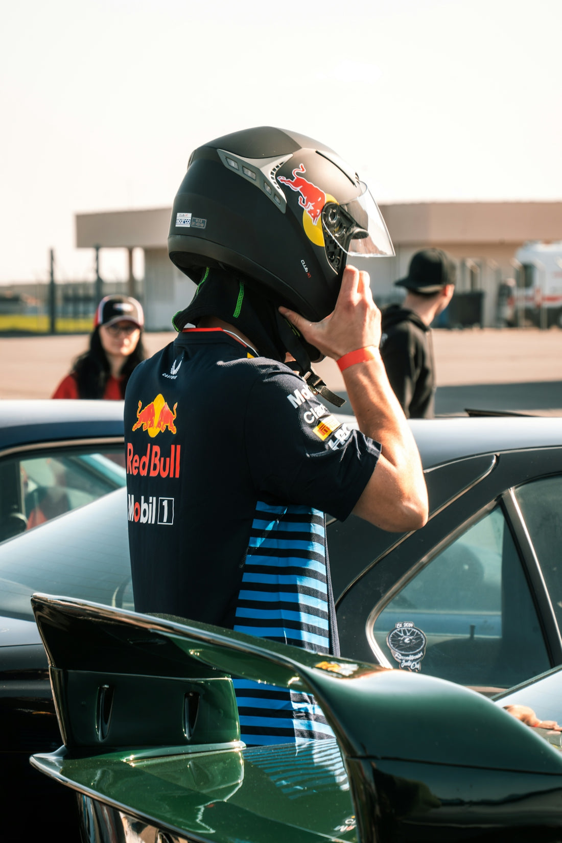 A person in a racing helmet adjusts their gear